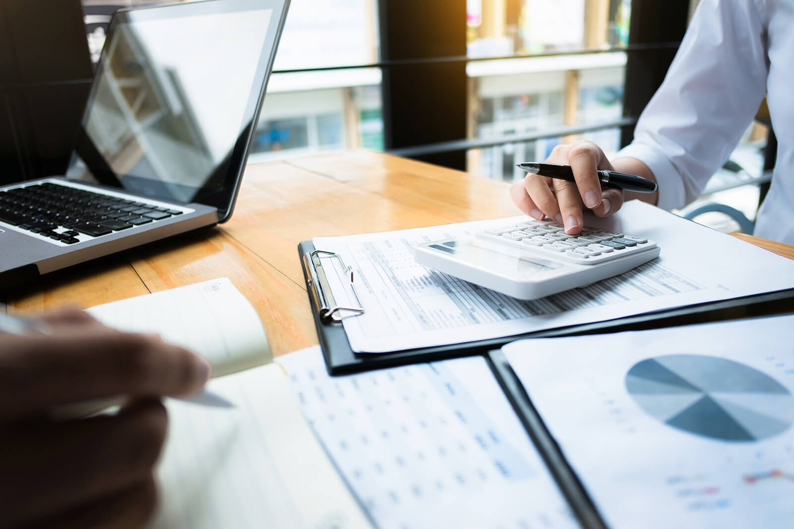 Person using a calculator while reviewing financial documents.