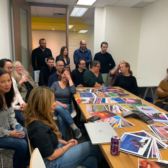 Team members gathered around a table reviewing printed materials in a collaborative meeting.