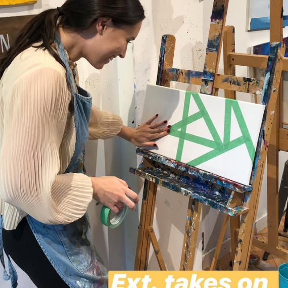 Team member taping a geometric design on a blank canvas during a painting activity.