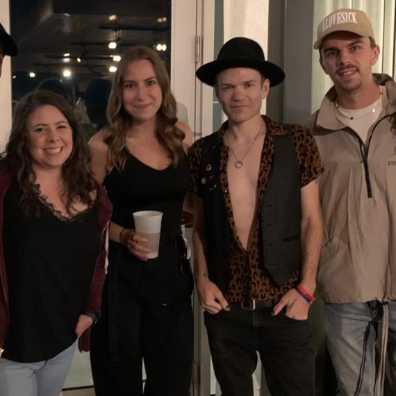 Group of colleagues posing with Sum 41 lead band member backstage at Scotiabank Arena.